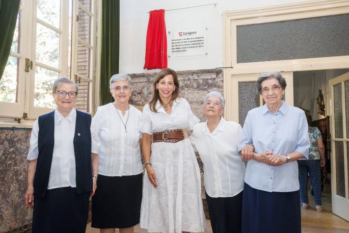 La alcaldesa, Natalia Chueca, junto a las Hijas de la Caridad, bajo la placa conmemorativa instalada en el recibidor de la Casa