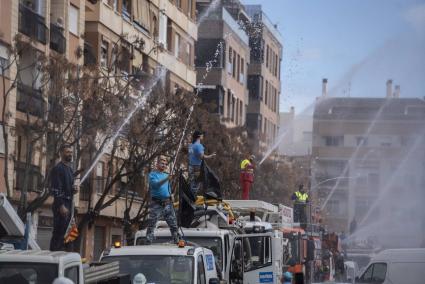 Compañeros del trabajador fallecido en un garaje de Benetússer hacen un arco de agua con las mangueras desde sus camiones