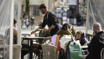 Un camarero sirve una mesa en la terraza de un bar.
