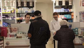 Dos farmac&eacute;uticos atiendes a dos clientes. Imagen de archivo.
